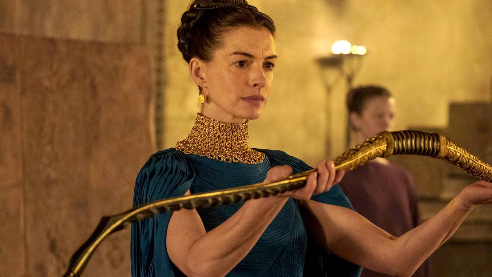 Anne Hathaway holding out a bow in The Odyssey