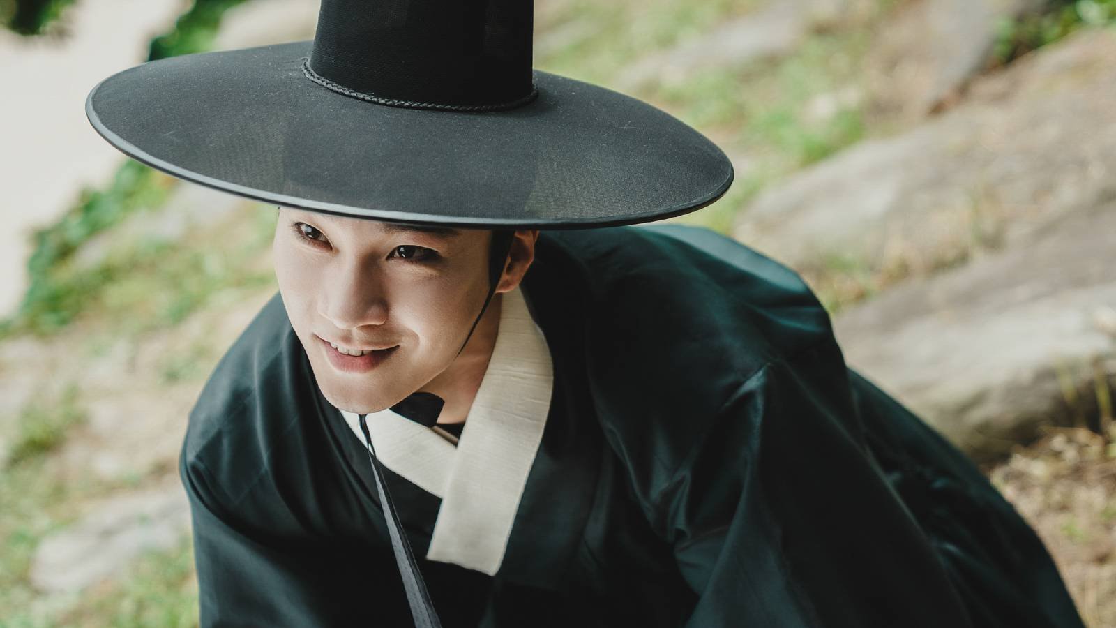 A man in Joseon Era clothes grinning darkly in The East Palace.