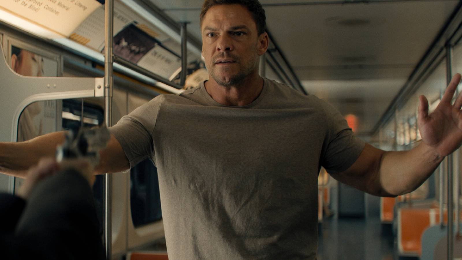 Alan Ritchson as Reacher being held at gunpoint